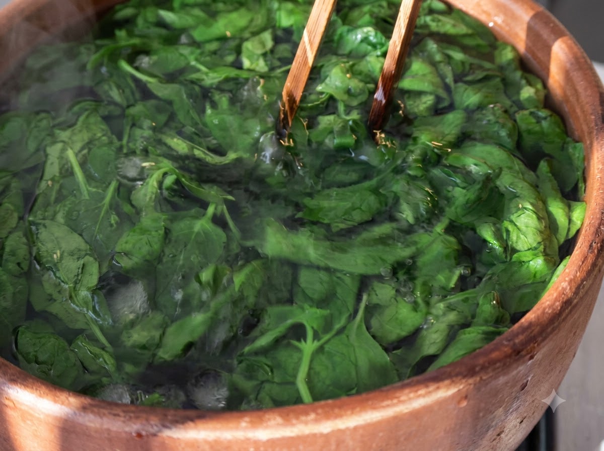 Blanched basil leaves submerged in ice water inside a wooden bowl with wooden chopsticks.